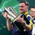 Luke Littler won his second straight PDC World Darts Championship title on Saturday night at London's Alexandra Palace. The eighteen-year-old sensation defeated Dutch rival Gian van Veen with a dominant 7-1 set score to retain his position as the world number one. Despite losing the first set in a close contest, Littler showed incredible resilience by winning the next seven sets in a row. This victory allowed him to claim the prestigious Sid Waddell Trophy and a record-breaking winner's purse of one million pounds. Littler is now the first player to successfully defend this specific world title since Gary Anderson achieved the feat in 2016. His performance throughout the evening was marked by high scoring and clinical finishes that left his opponent with few opportunities to respond. The final match at the iconic Ally Pally venue featured two of the youngest stars in the history of professional darts. Gian van Veen entered the contest in excellent form after his semi-final win over Gary Anderson and initially took a 1-0 lead. The Dutchman survived several set darts from Littler to win the opening set in a final-leg decider. However, the momentum shifted quickly in the second set as Littler began to find his rhythm with a series of 180s. The young Englishman won ten consecutive legs during one phase of the match to build a commanding lead over his opponent. His match average remained above 105 for most of the night, highlighting the consistent power of his scoring visits. +1 Van Veen continued to throw high-quality darts but struggled to keep pace with the relentless accuracy of the defending champion. The Dutch star maintained an average of over 100 throughout the final but found himself under pressure on nearly every visit to the board. A standout moment in the match occurred during the final set when Littler completed a magnificent 147 checkout to seal his dominance. This remarkable finish brought the crowd to their feet and served as a reminder of the generational talent Littler possesses. While Van Veen managed to land several maximums and showed great fighting spirit, he was unable to break Littler’s rhythm as the sets continued to go in favor of the Englishman. The triumph marks another significant milestone for the player known to fans as The Nuke. Since reaching the final as a teenager in 2024 and winning his first world title in 2025, Littler has become a global phenomenon. His ability to remain calm under the intense pressure of a world final has redefined the expectations for young players in the sport. The rivalry between Littler and Van Veen is expected to be a major narrative in professional darts for many years to come. Following the final double, Littler celebrated with his family and supporters while the fans at Alexandra Palace chanted his name. He is now officially the youngest player to ever win multiple world championships in the history of the PDC. The trophy presentation capped off a historic night for the sport as the prize money for the event reached new heights. The increased financial rewards and record television viewership reflect the massive growth of darts under the influence of its new stars. Littler remarked after the match that the prestige of the trophy was his main goal rather than the financial gain. He expressed a desire to continue his winning streak and stay at the top of the world rankings for as long as possible. Gian van Veen moves up to world number three following his impressive performance in this year's tournament and will likely be a top contender in future major events. For now, Luke Littler stands alone as the undisputed king of the darting world.